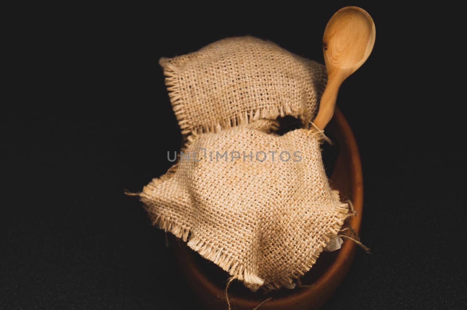 Honey pots with linen cloth with wooden spoon on dark background