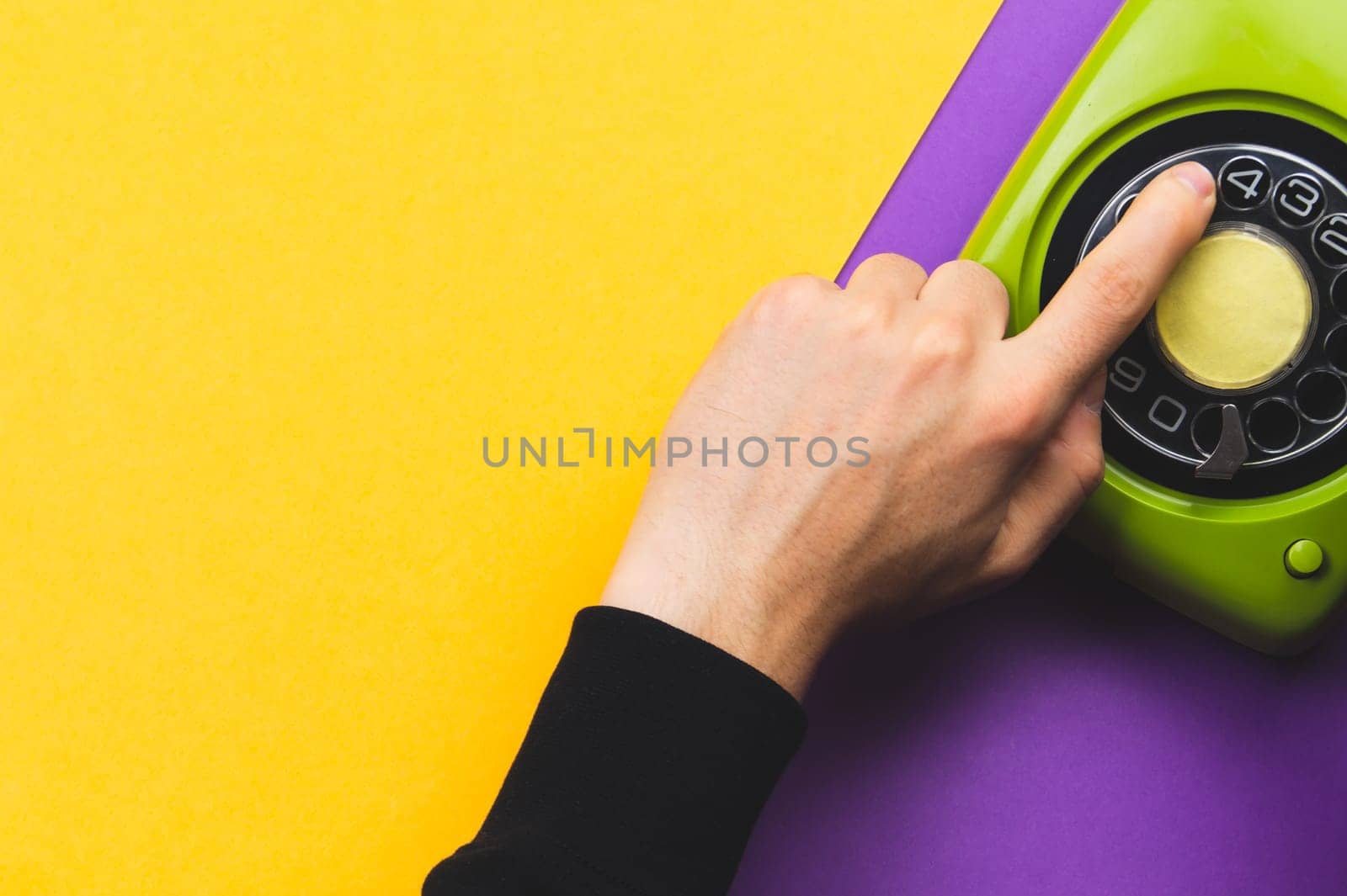Hand dialing a number on a classic phone with round dial. vintage green telephone. copy space