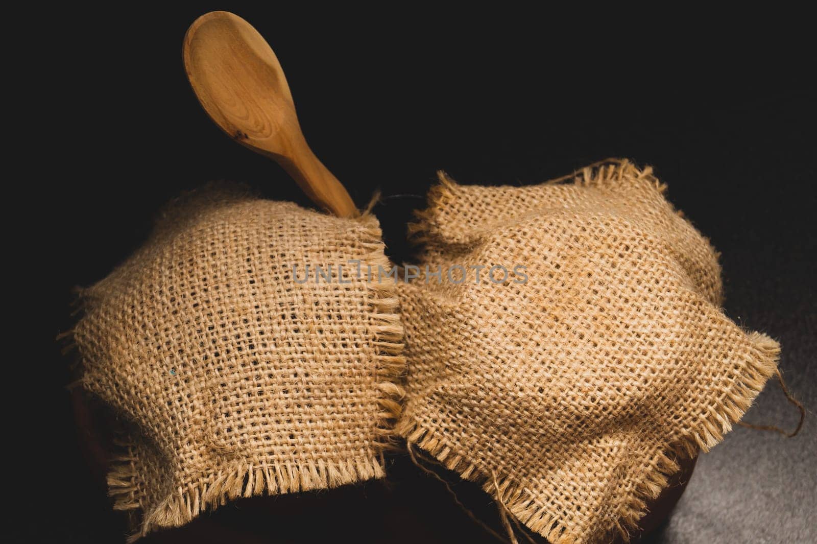 Honey pots with linen cloth with wooden spoon on dark background