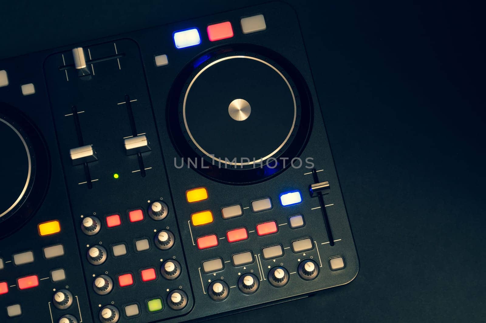 Dj sound mixer controller with knobs and sliders close up. audio mixing deck with turntables at dark with illuminated controls