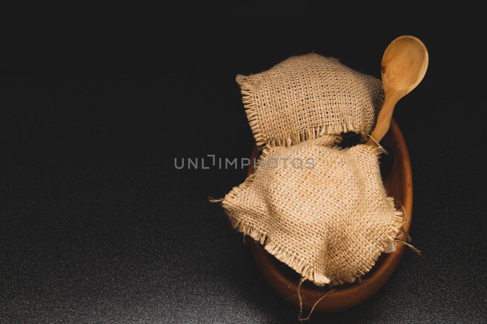 Honey pots with linen cloth with wooden spoon on dark background