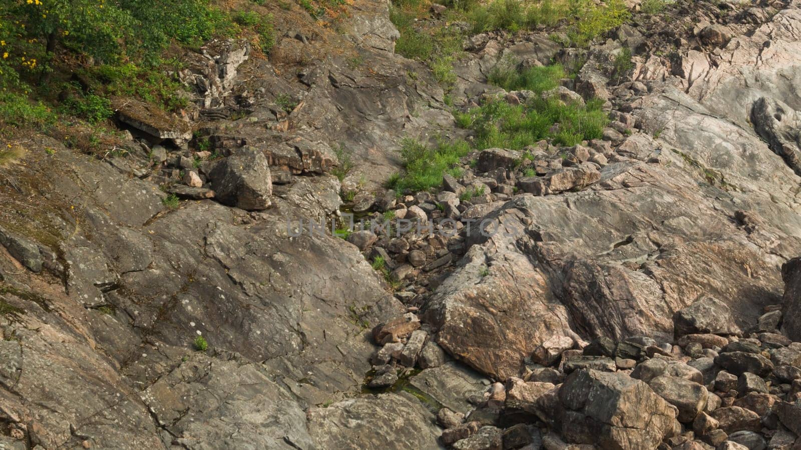 Rock of layered stone overgrown with grass and moss. texture of stone rocks. stone background