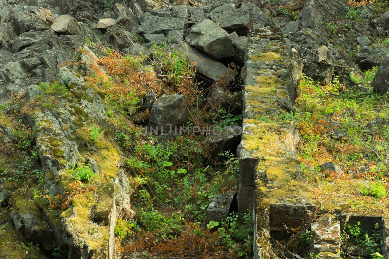 Rock of layered stone overgrown with grass and moss. texture of stone rocks. stone background