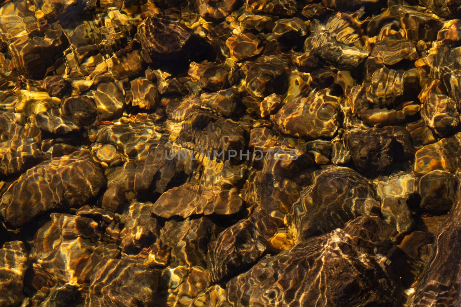 Shiny transparent water. clear water with pebbles and stone on the bottom. shining reflections of sun rays and ripples on the water surface
