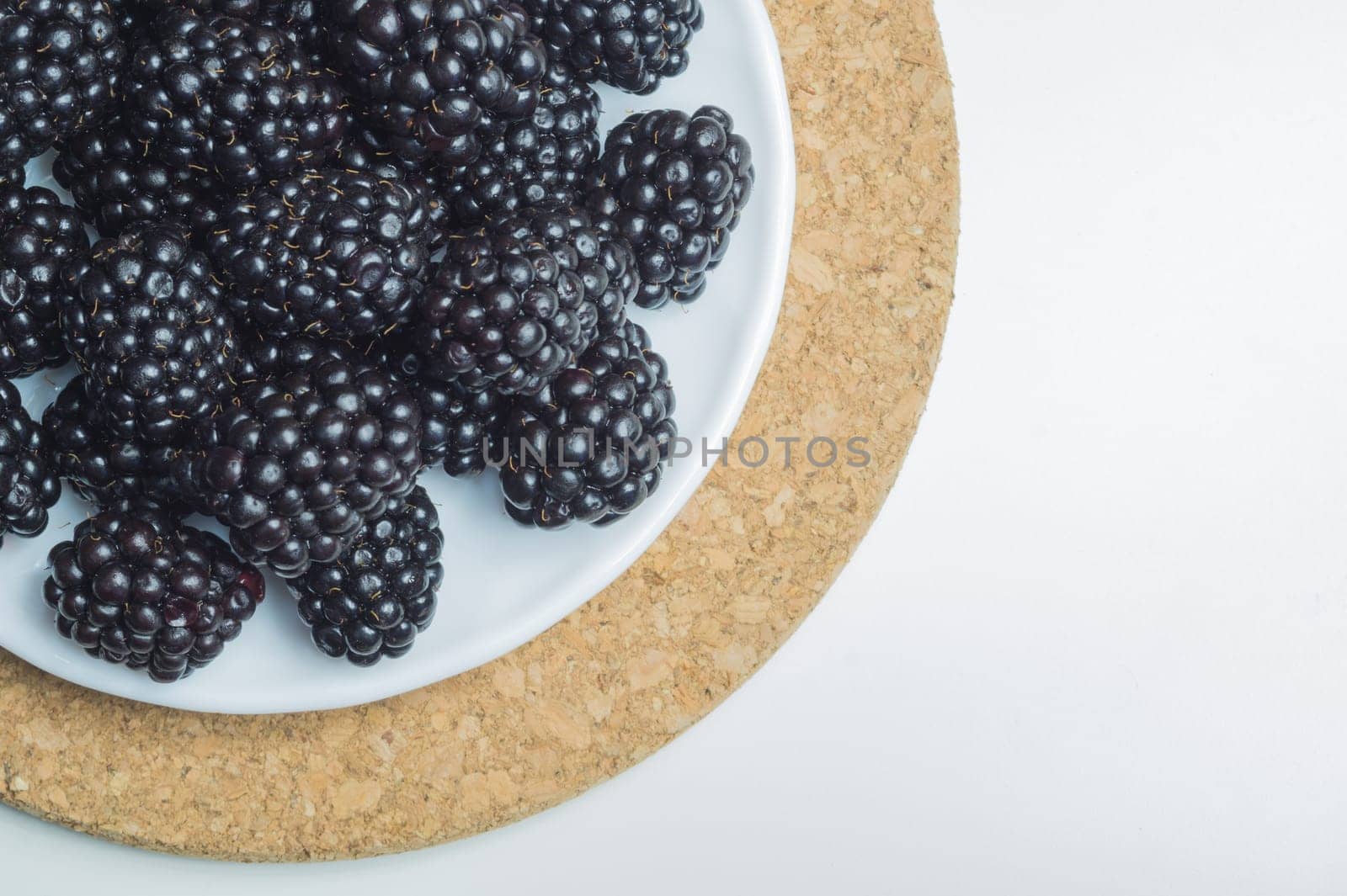 Blackberries on a plate isolated on white background. fresh berries with copy space