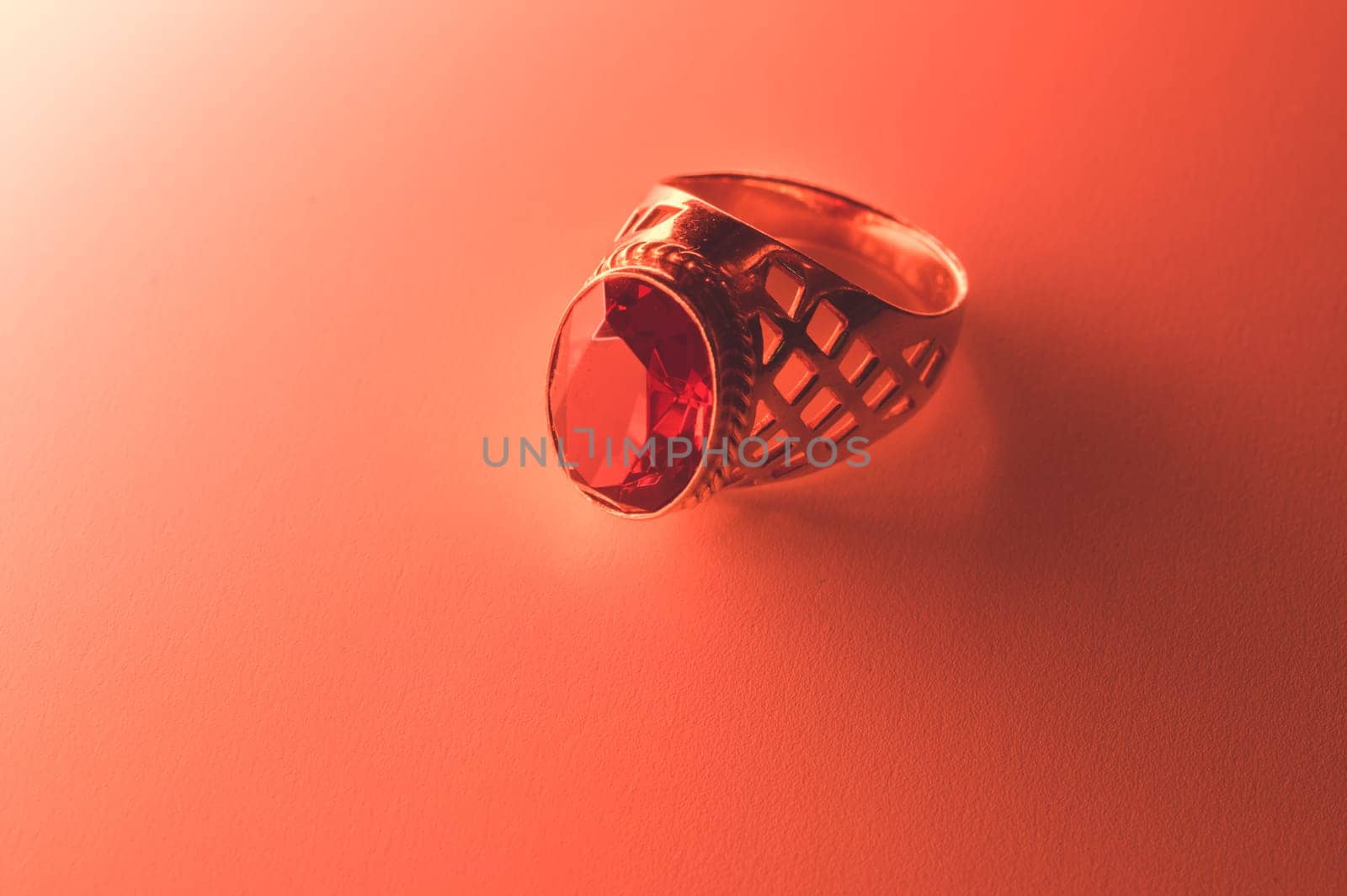 Golden ring with ruby under red light background