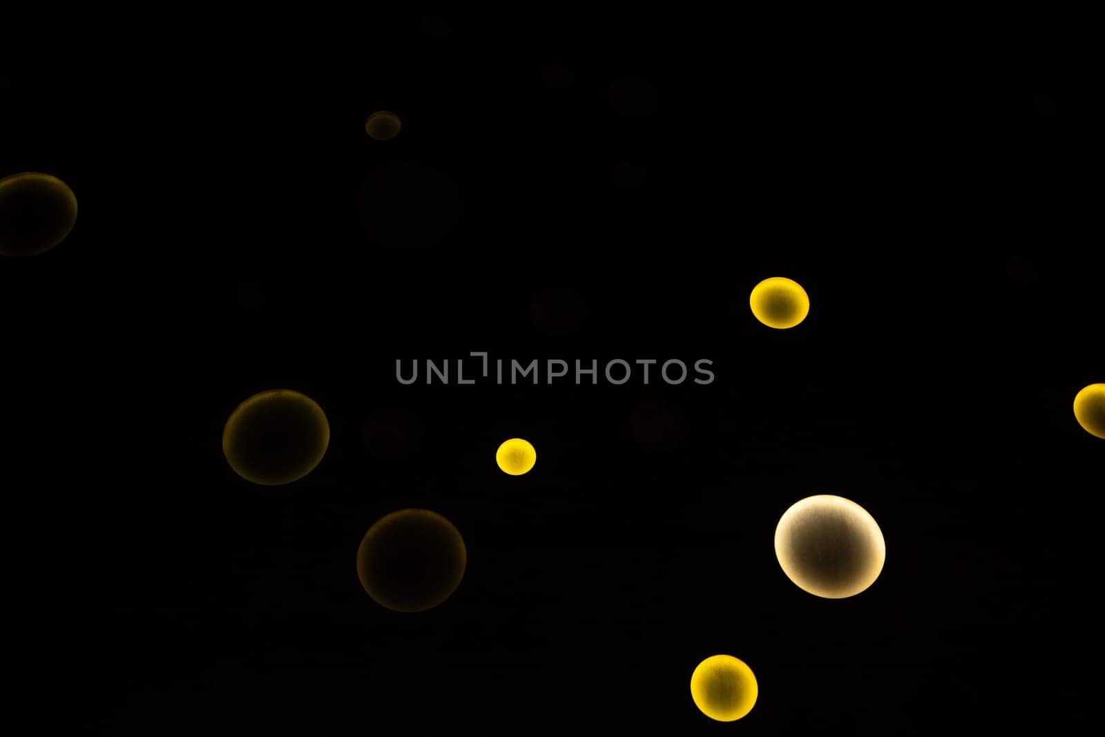 White and yellow circles of different sizes glow on a black background. High quality photo