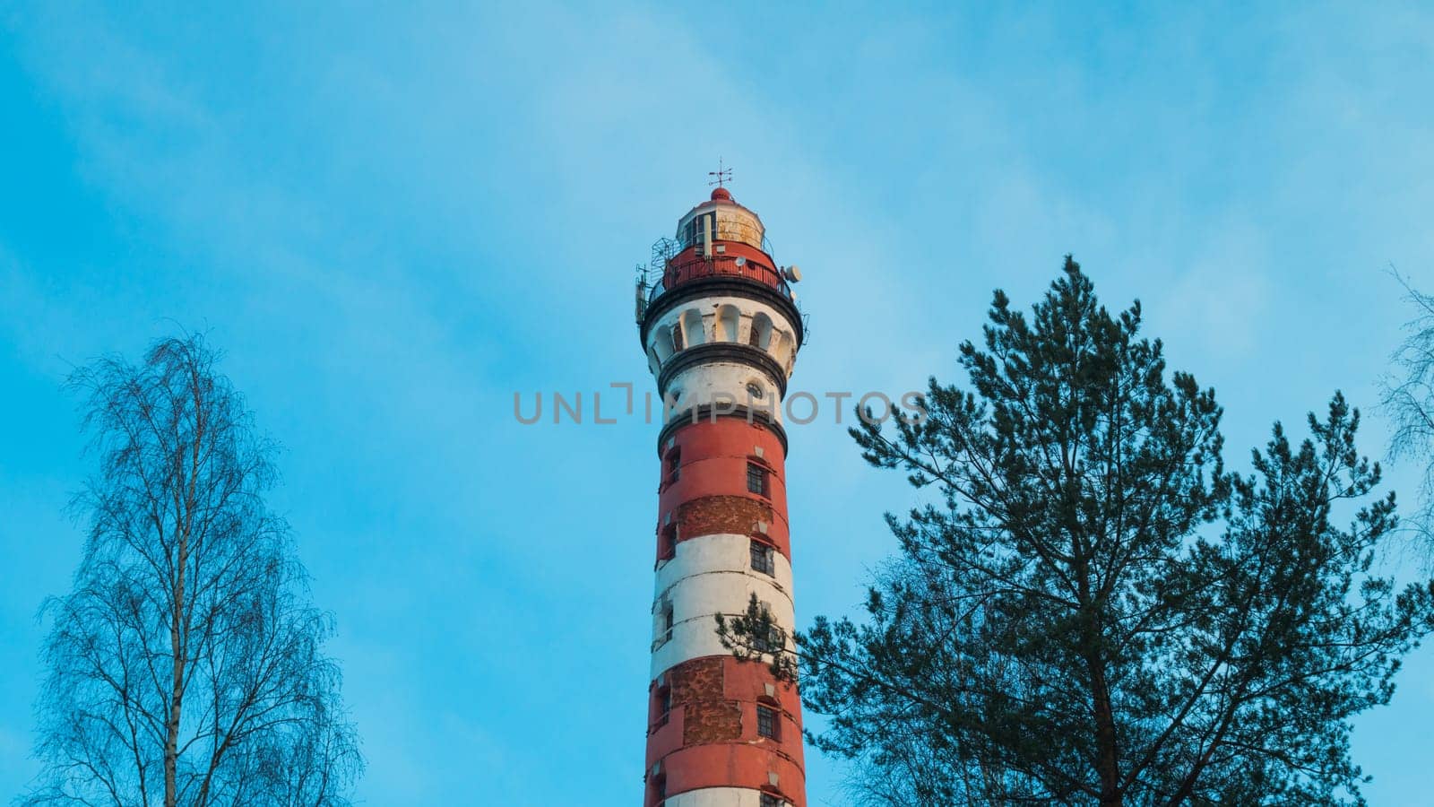 Lighthouse in the forest between the trees. red and white lighthouse background