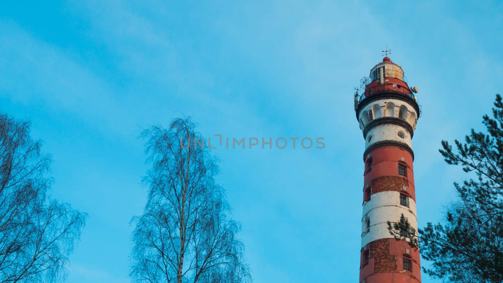 Lighthouse in the forest between the trees. red and white lighthouse background