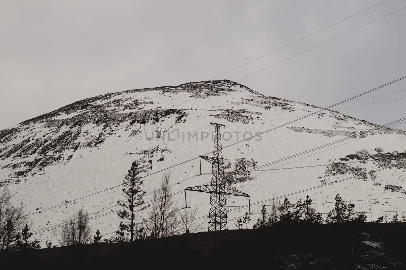 Mountain landscape background. snowy hills and forest. industrial power lines in mountains