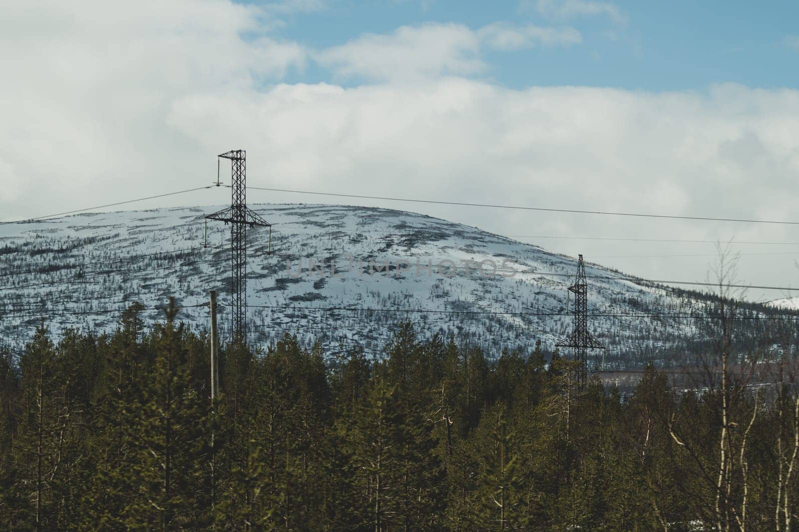 Mountain landscape background. snowy hills and forest. industrial power lines in mountains