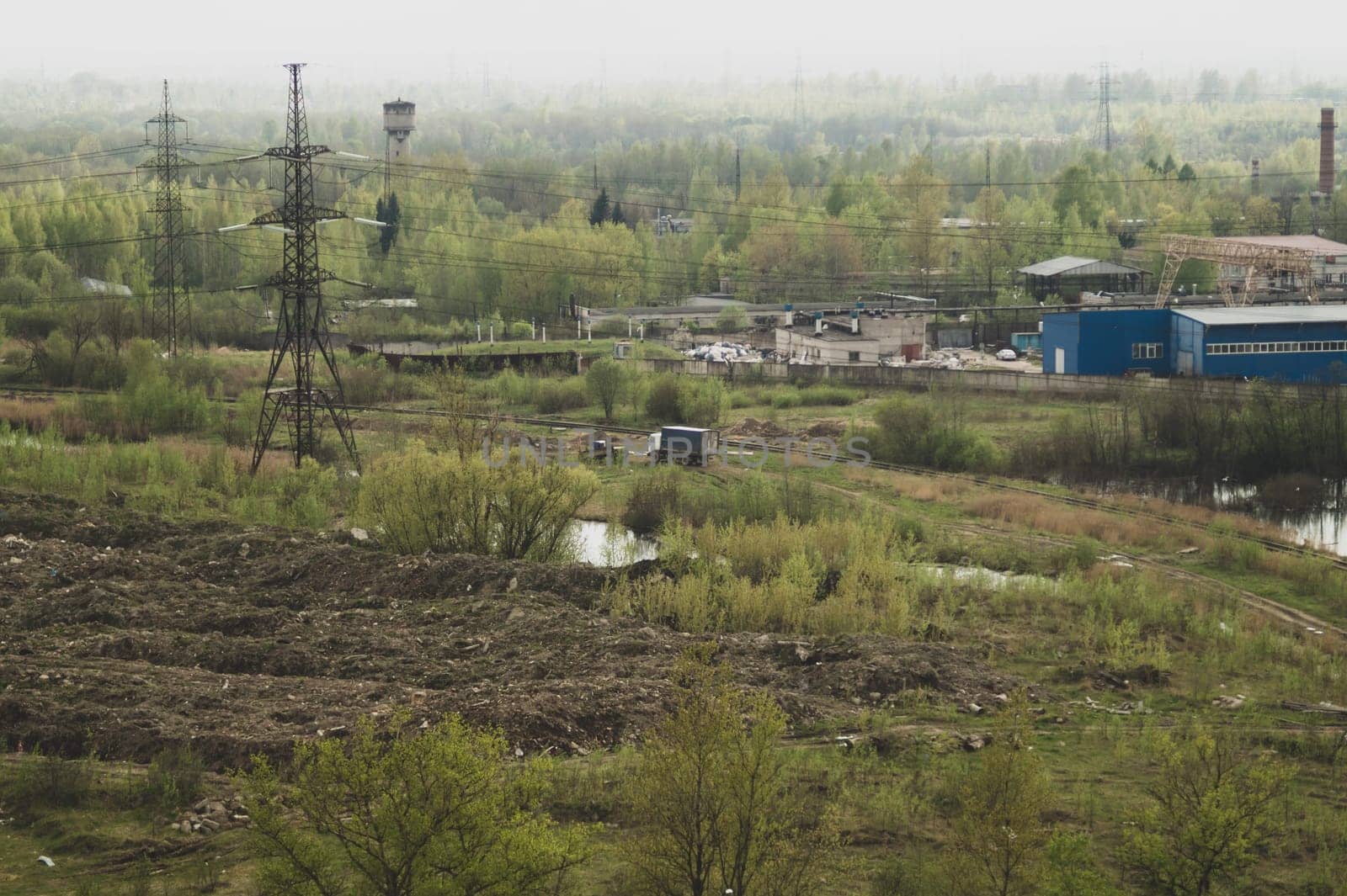 Truck car among forest near the factory. power lines. manufacture building. railway in marshland. aerial view