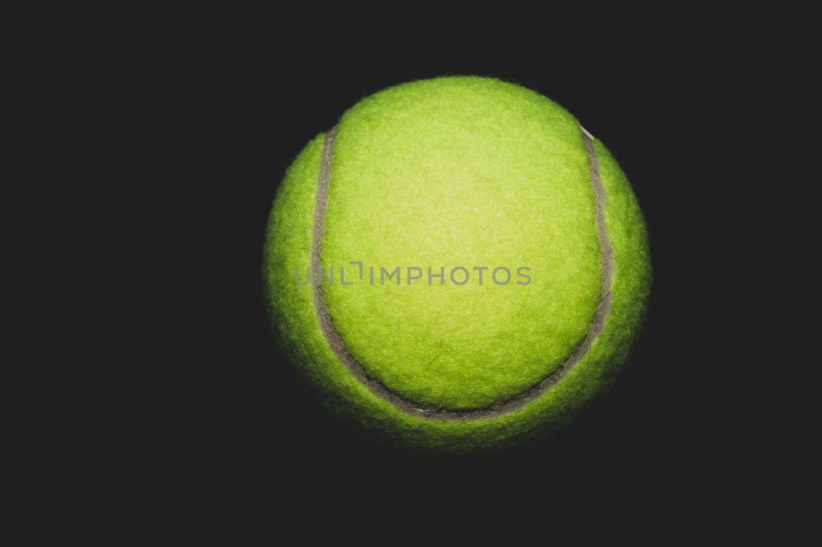 green tennis ball isolated on black background. sport equipment