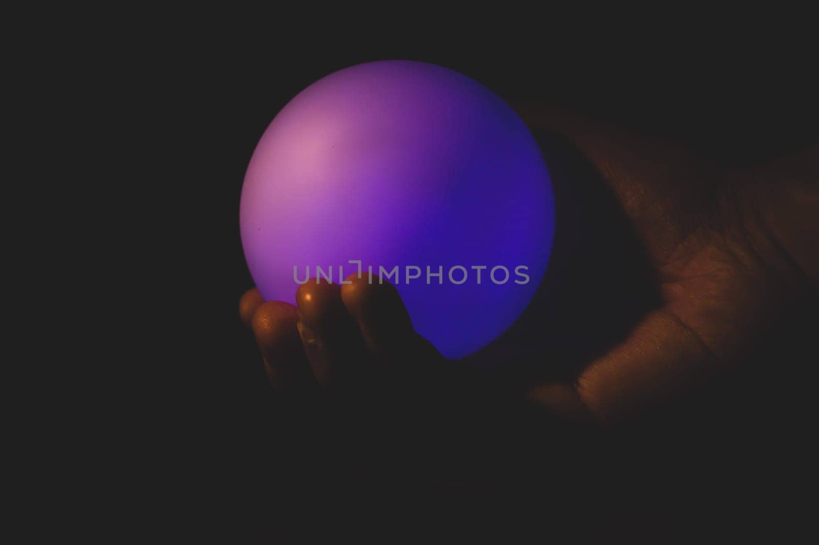 Hand holds a luminous sphere in the dark