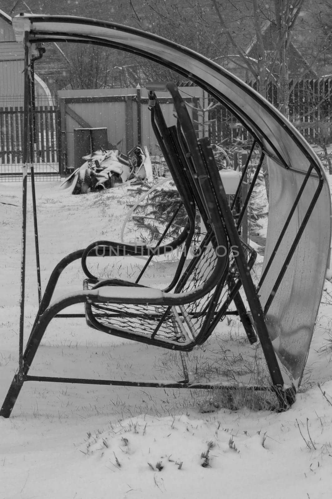 Swing in a snowy garden. backyard of a country house in winter