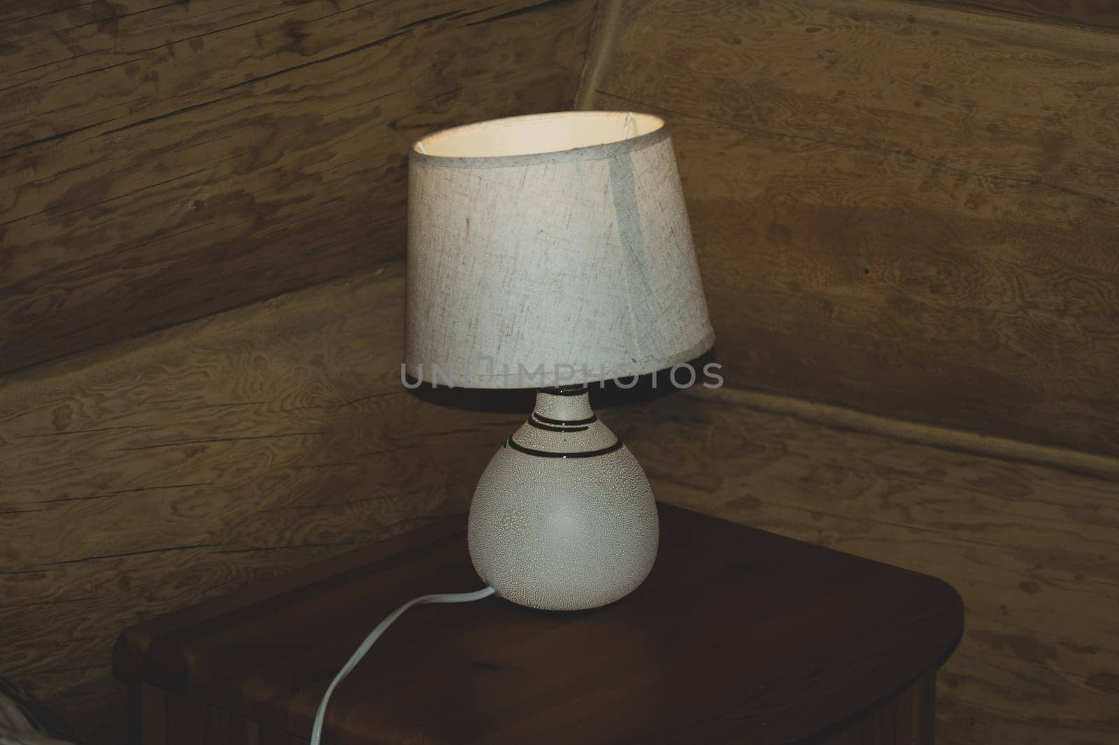 Luminous desk lamp with lampshade on dark glass surface with reflection