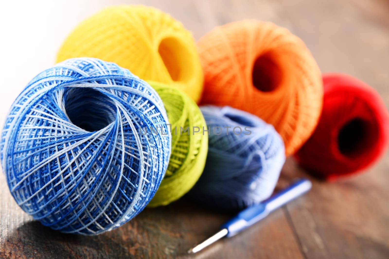 Colorful yarn for crocheting and hook on wooden table