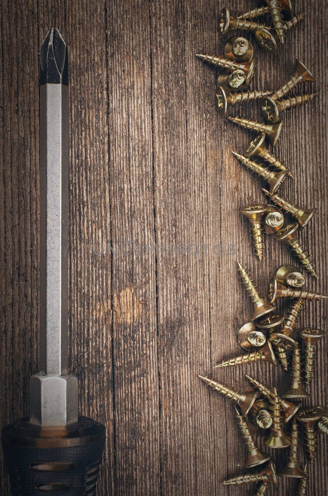screwdriver and screws on wooden background