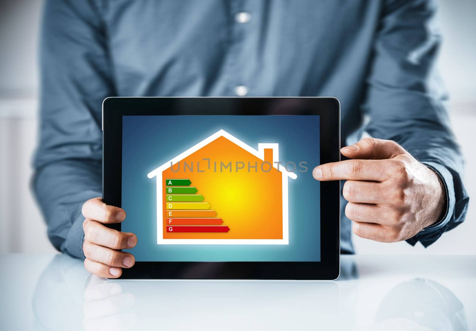 Man pointing to an online energy efficiency rating chart for a house displayed on the screen of a tablet computer, close up of his hands