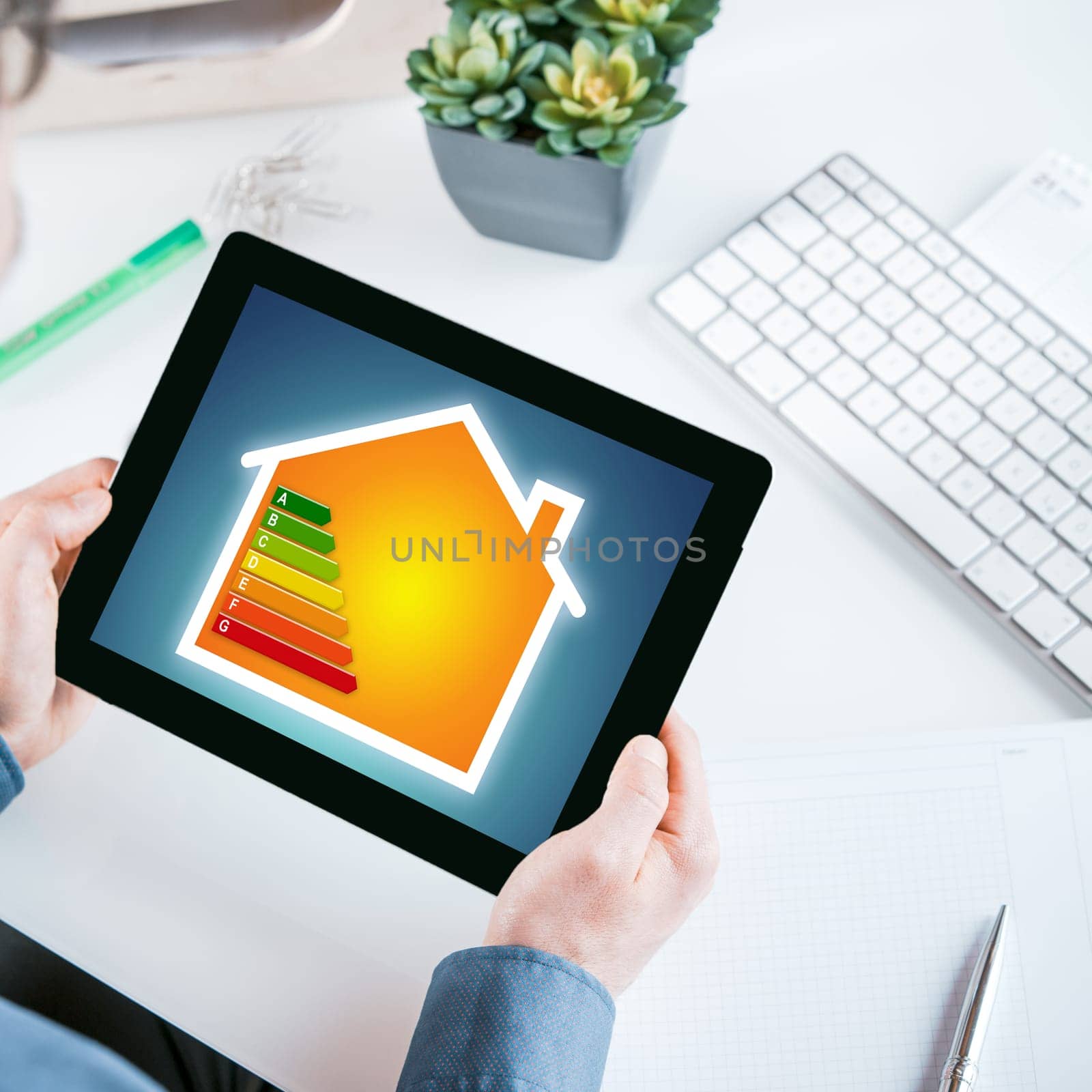 Smart home online energy control concept with the hands of a businessman holding a tablet displaying an energy consumption and efficiency rating chart