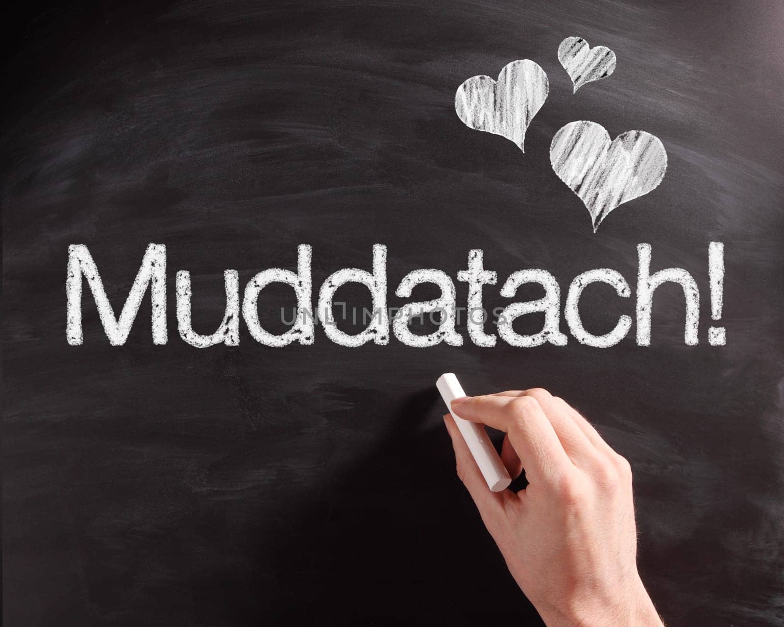 Human Hand Writing a Conceptual Muddatach Text on Black Chalkboard with Heart Shapes.