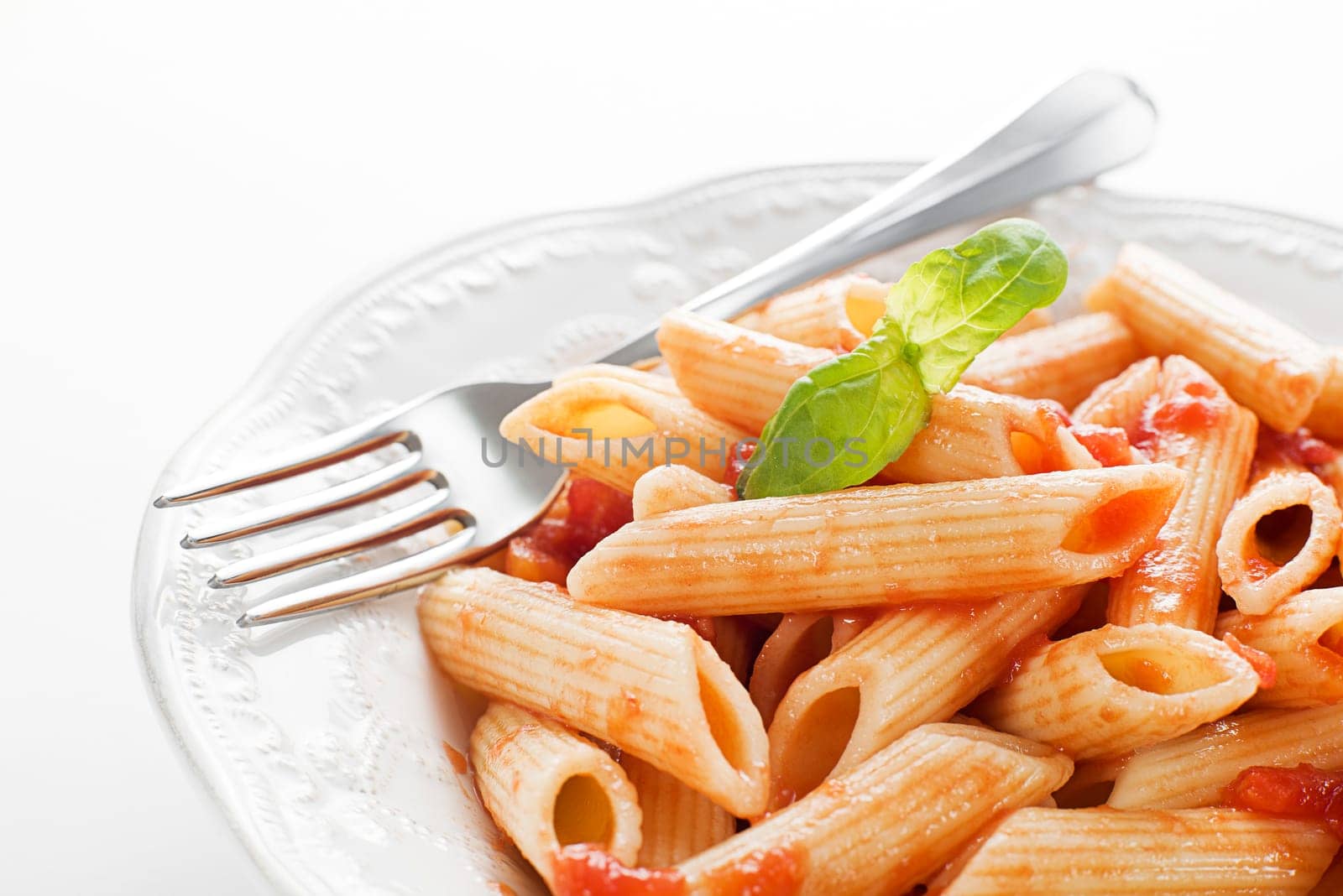 Plate of penne pasta with tomato sauce and basil