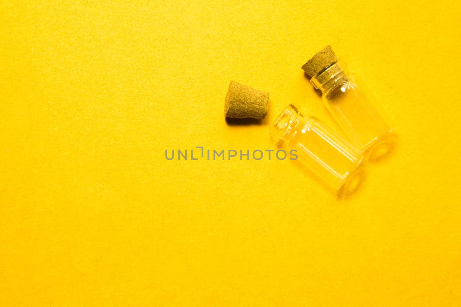 Empty little bottles with cork stopper isolated on yellow. glass vessels. transparent containers. test tubes. copy space