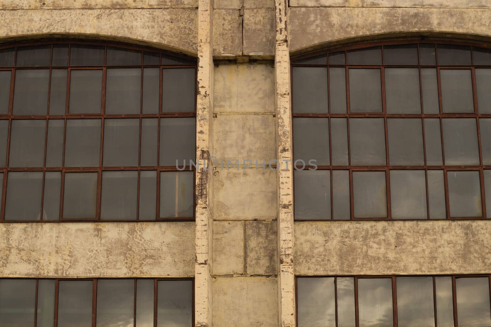 Big windows of the factory on the cement wall background