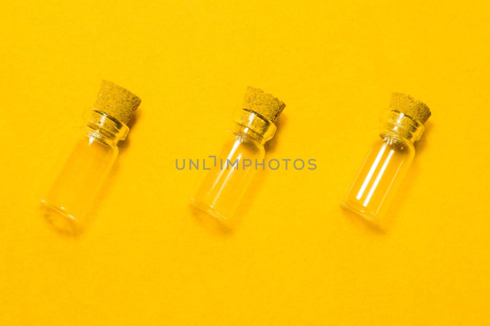 Empty little bottles with cork stopper isolated on yellow. glass vessels. transparent containers. test tubes