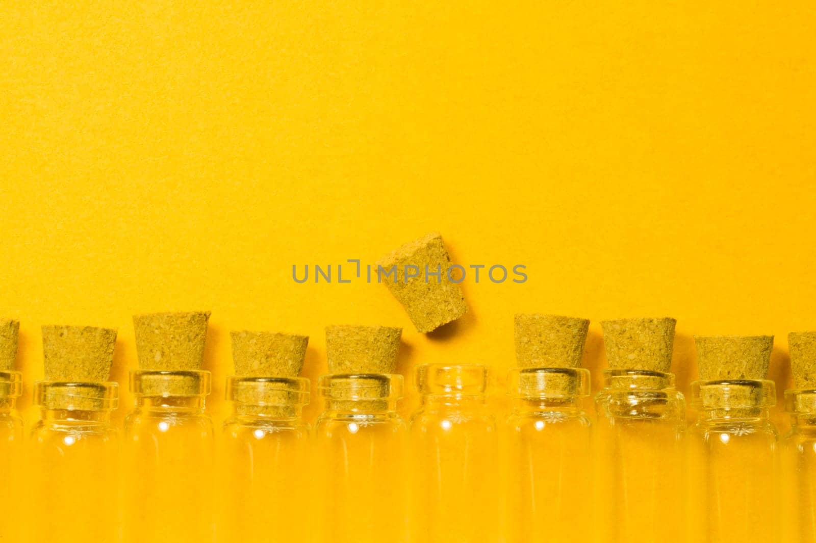 Empty little bottles with cork stopper isolated on yellow. glass vessels. transparent containers. test tubes
