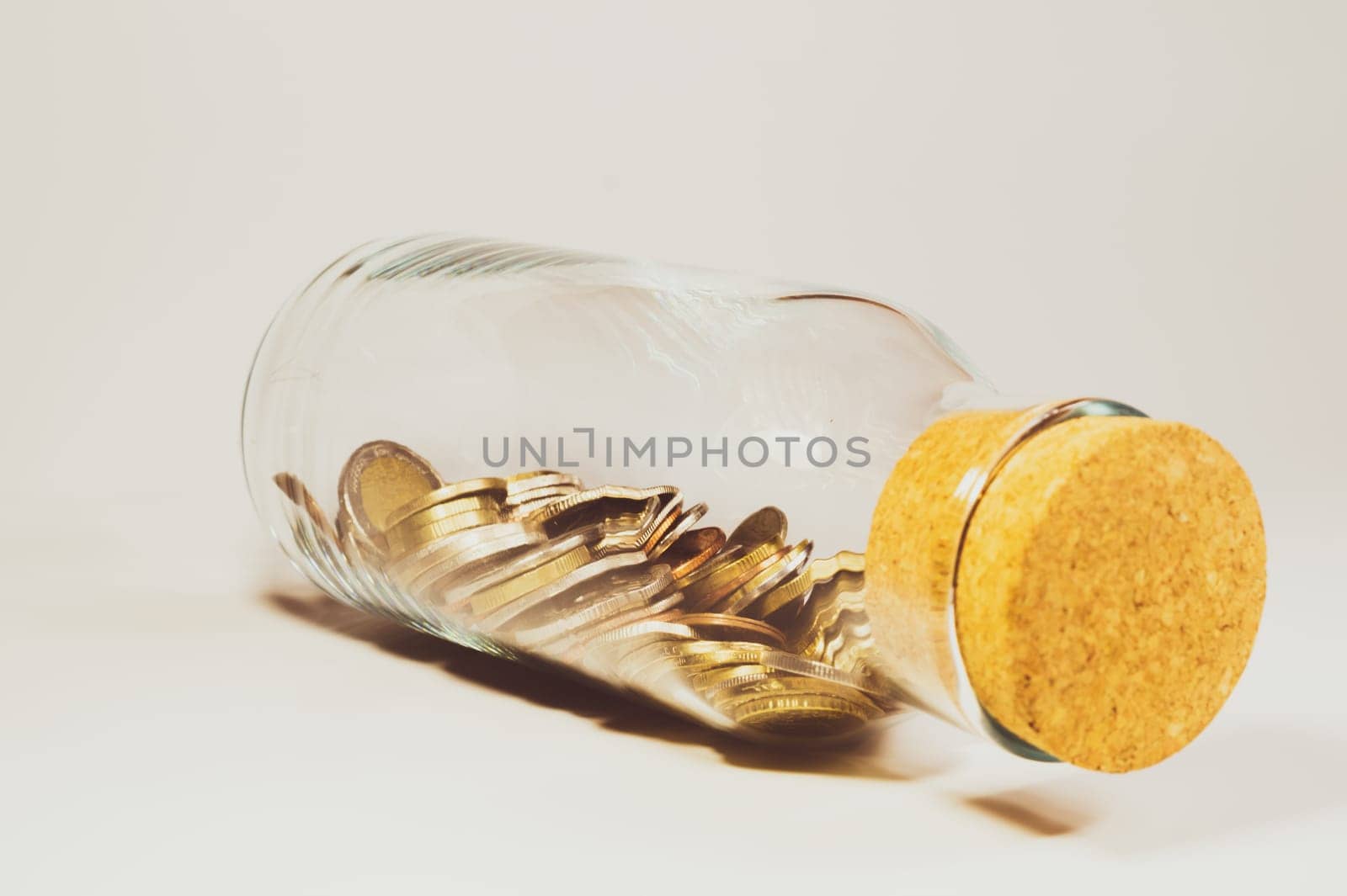 Glass jar with cork stopper and filled with international coins from various countries. transparent moneybox. finance storage concept