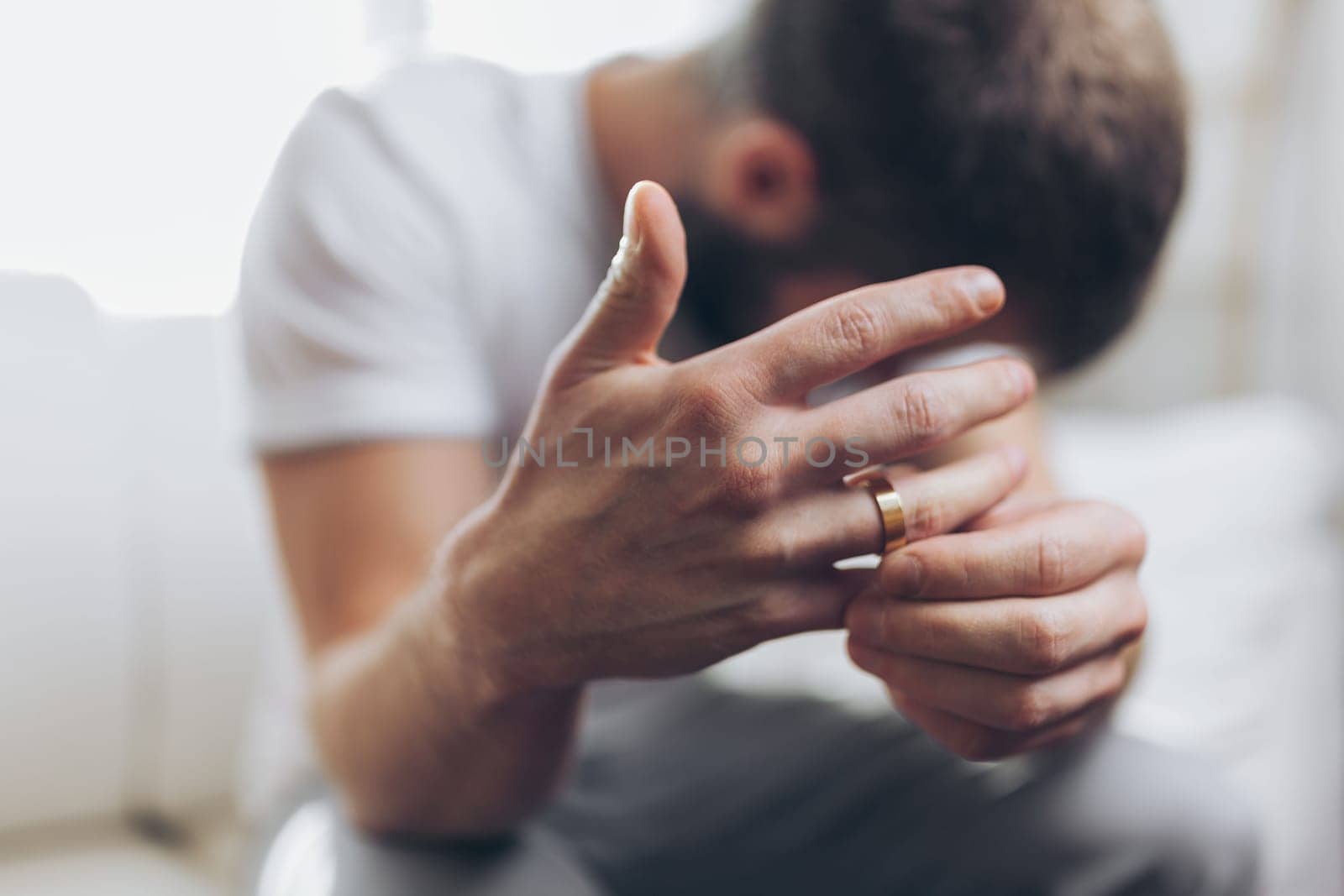 Heartbroken man at home holding a wedding ring