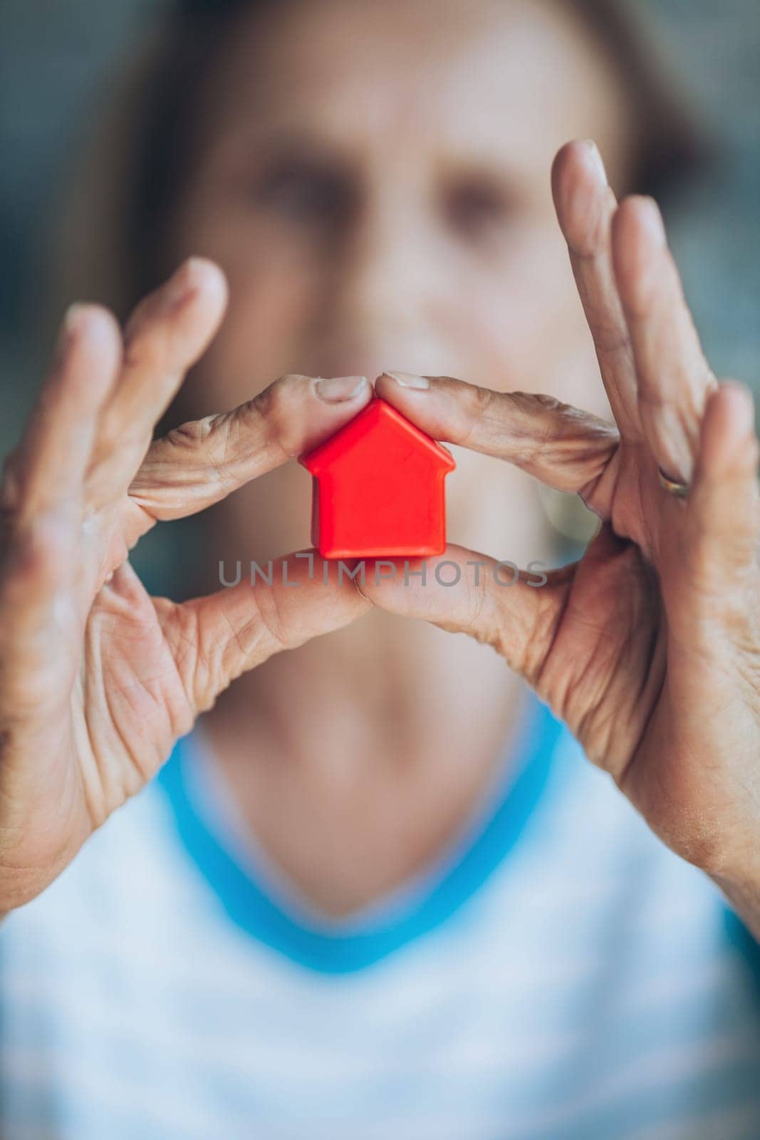 Elderly woman holding a small house in her hands