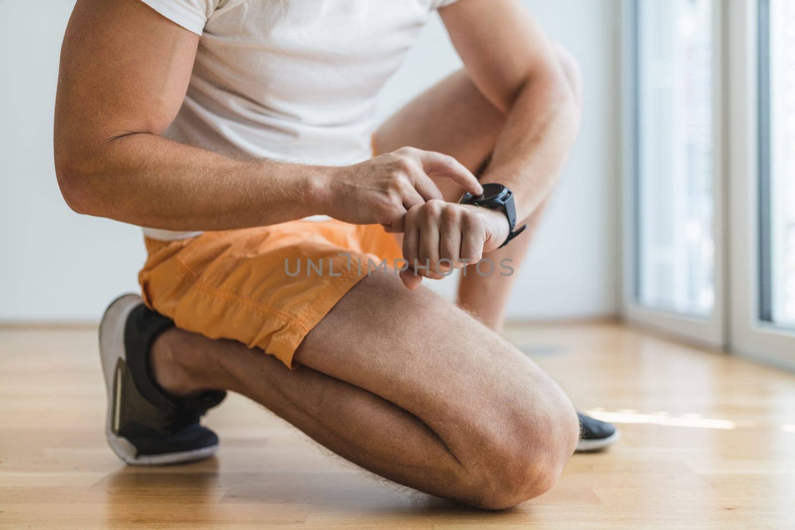 Handsome young man working out at home with a smart watch