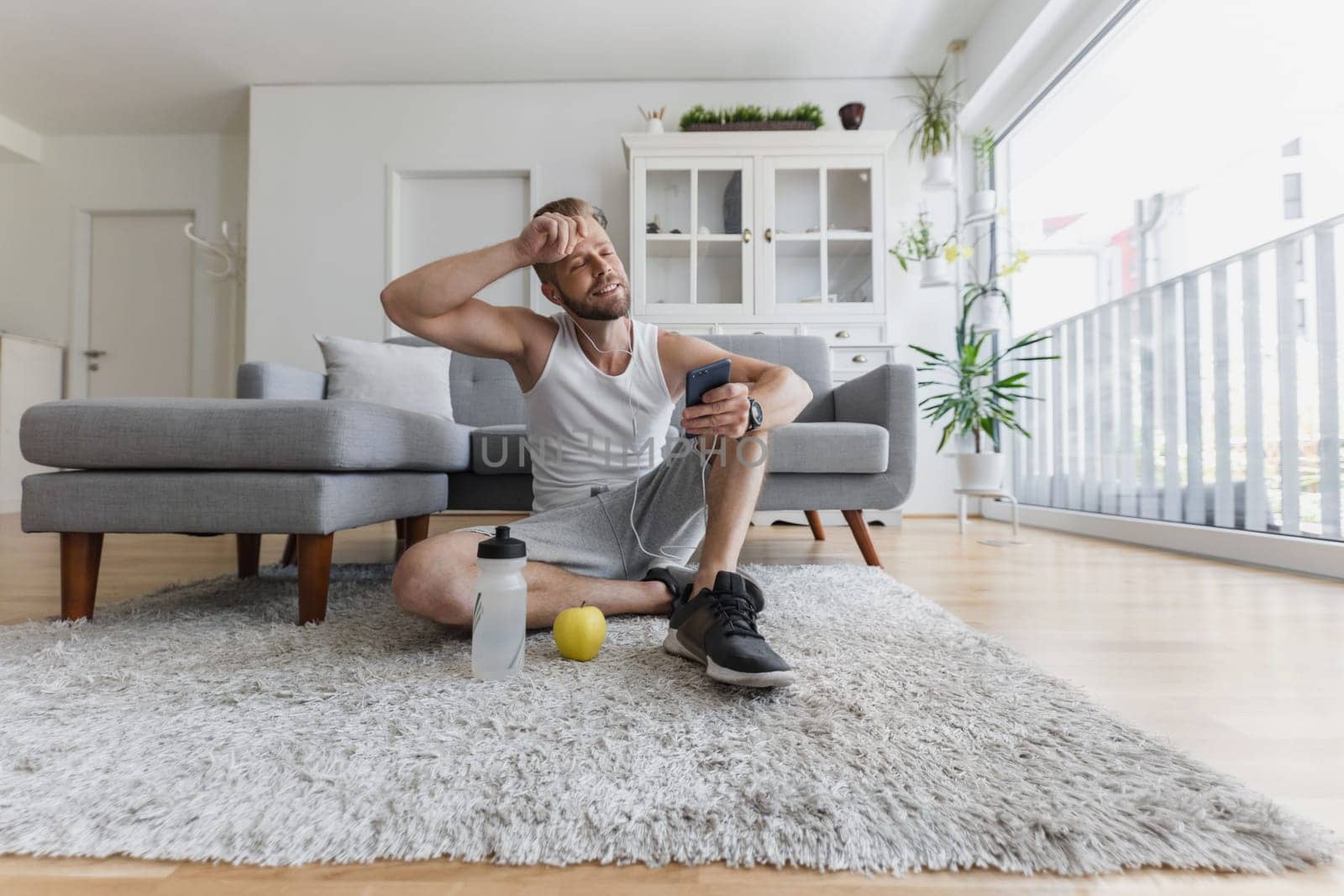 Handsome young man working out at home in the living room