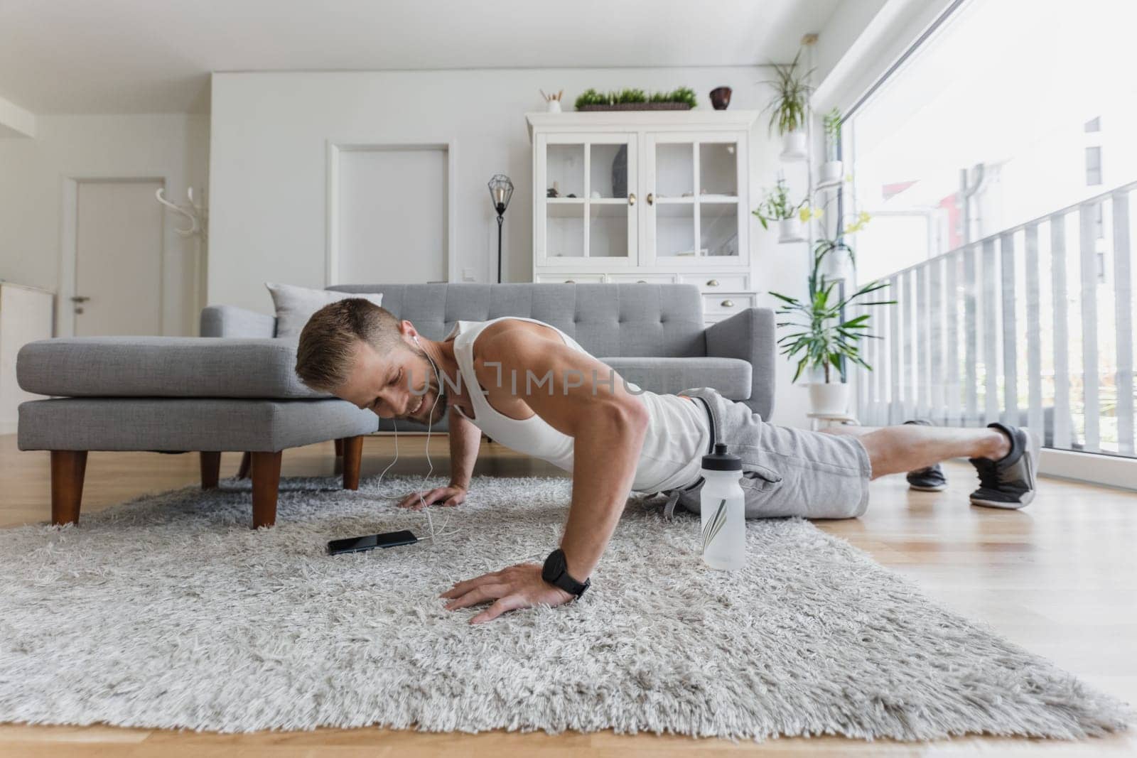 Handsome young man working out at home in the living room