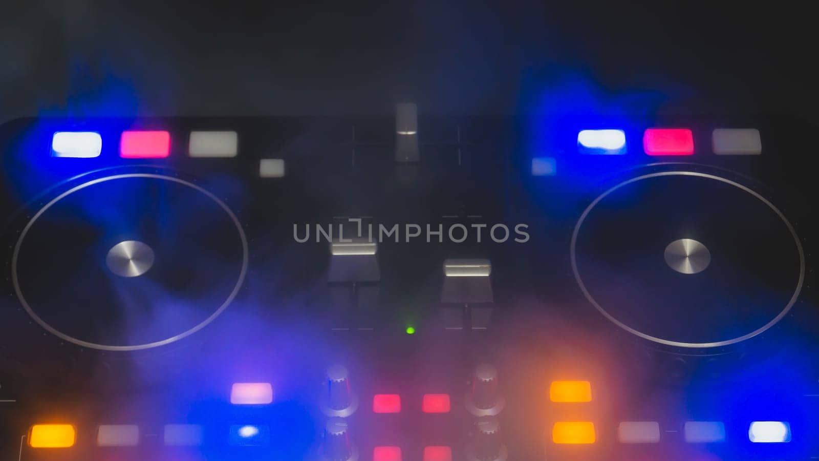 Dj sound mixer controller with knobs and sliders close up. audio mixing deck with turntables at dark with illuminated controls