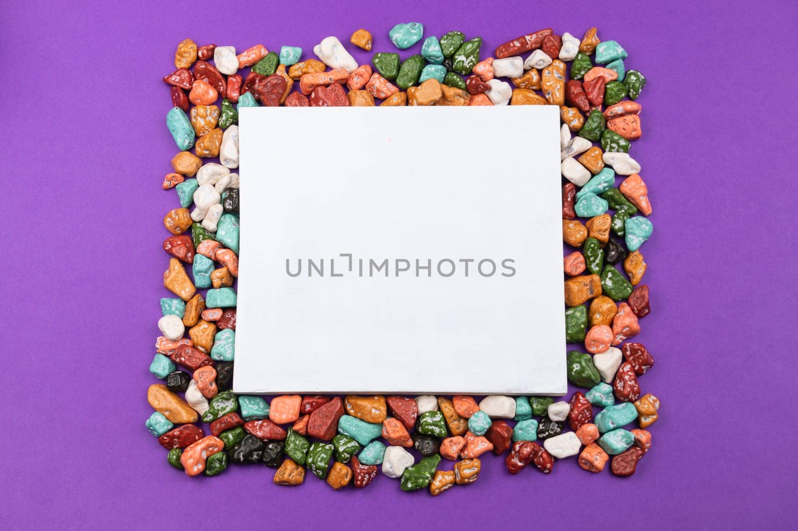 Candy pebbles. sweets in the form of colored stones. frame made from colorful candies with a white space in the middle