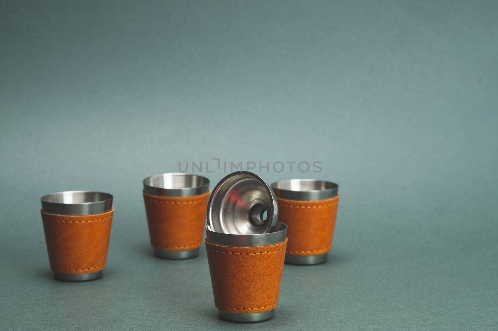 Metallic shot glasses and funnel. travel shot glass for alcohol with leather casing over the stainless steel. personal accessory set. copy space
