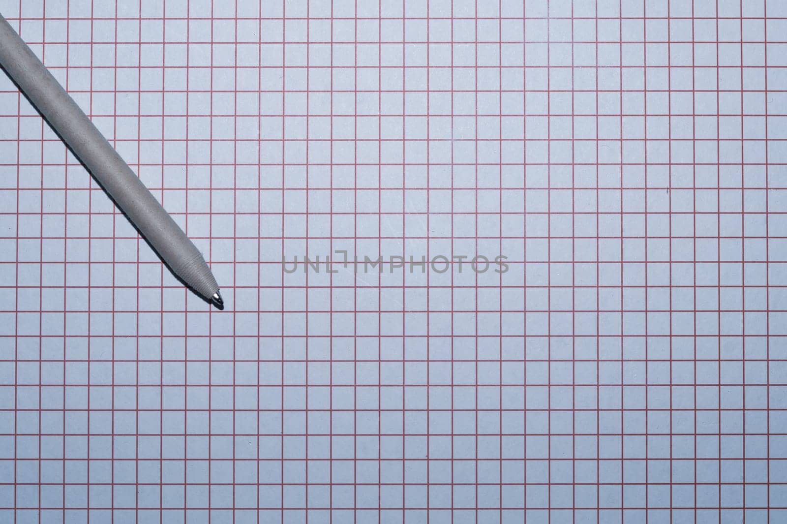 Pen lies on checkered paper. squared grid surface