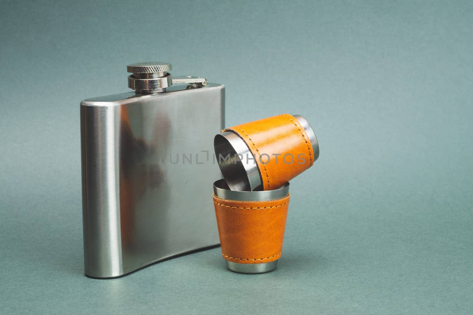 Stainless steel flask with pair of shot glasses. travel shot glass for alcohol with leather casing over the metal. personal accessory set