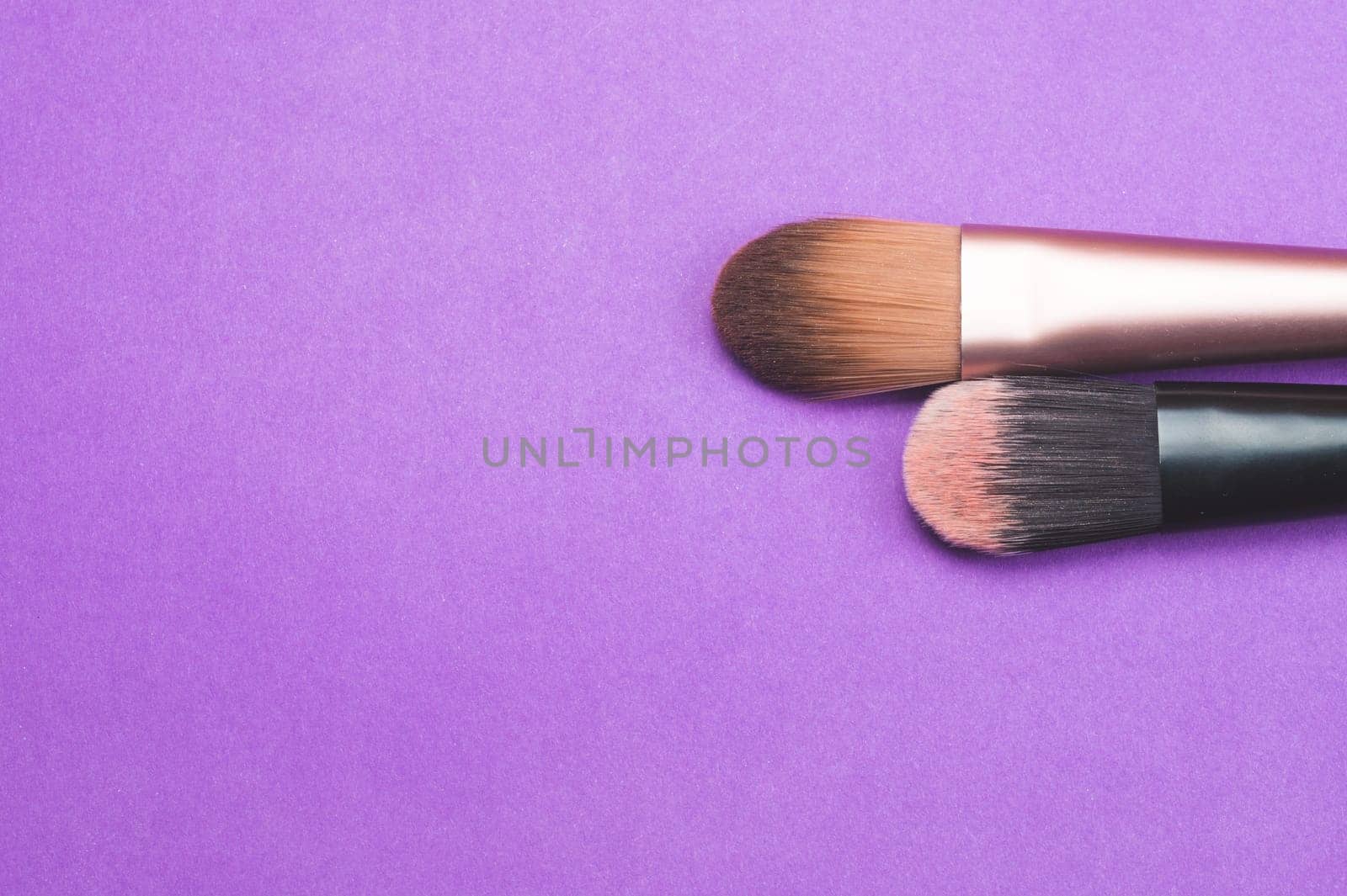 Makeup brushes on purple background. various cosmetic brushes close up. skin care accessories