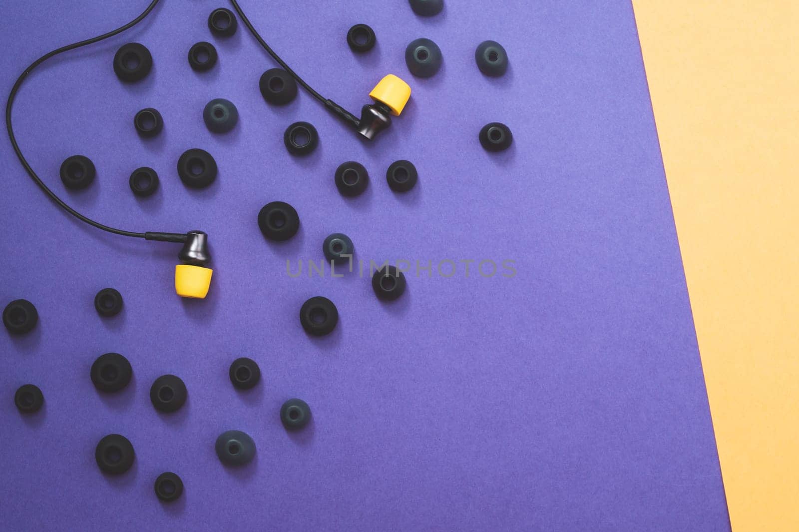 Individuality concept. earphones with yellow ear cushions between of gray embouchures. in-ear headphones. modern style. audio equipment