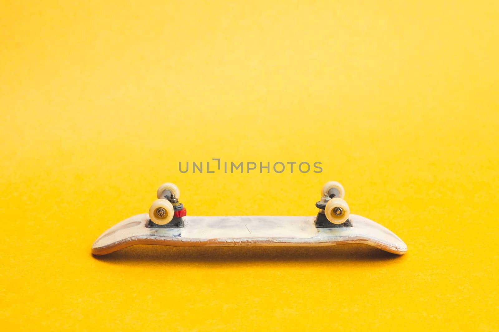 Small skateboard on yellow background. tiny skate for fingers. fingerboard close up. copy space