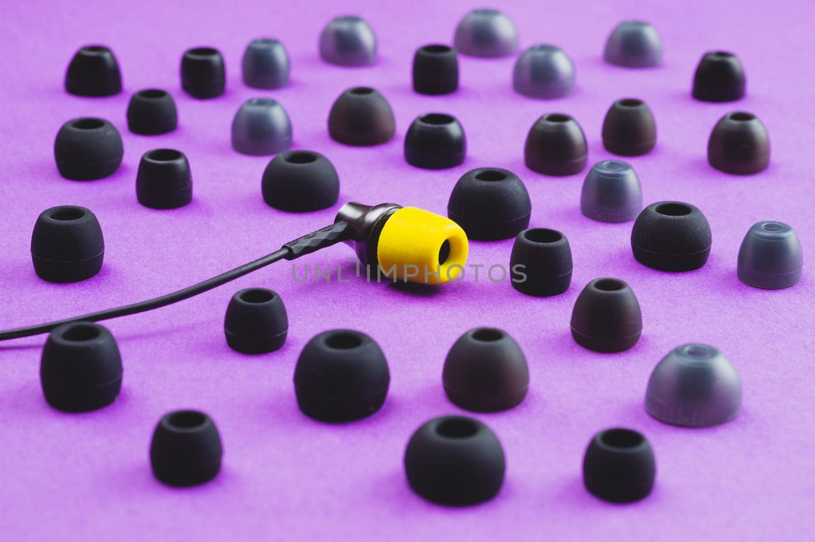 Individuality concept. earphone with yellow ear cushion between of gray embouchures. in-ear headphones. modern style. audio equipment