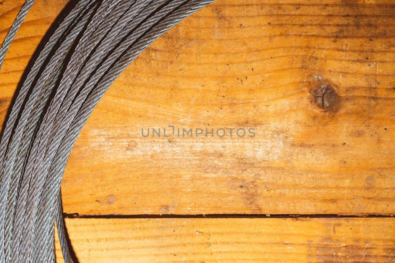Steel cable on wooden background. hank of metal rope lies on the table. work tool