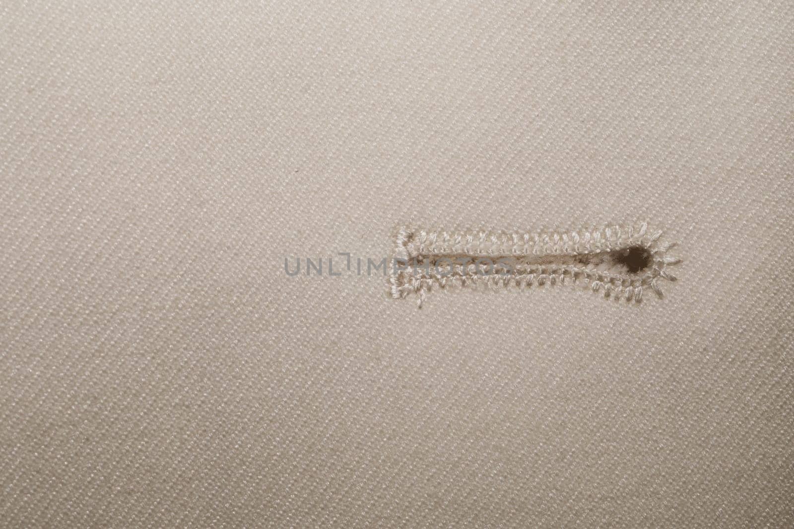 Beige fabric with a button hole. vintage jacket detail. textile close up background