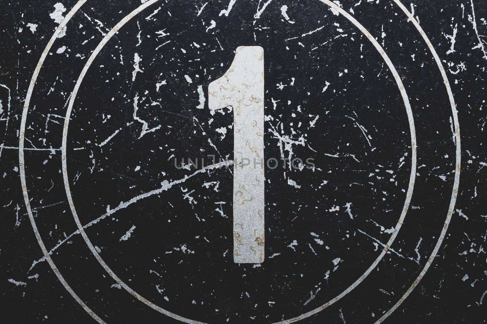 Number one painted on a metal surface. black iron plate with digit 1. scratched paint on steel. rough texture. industrial background