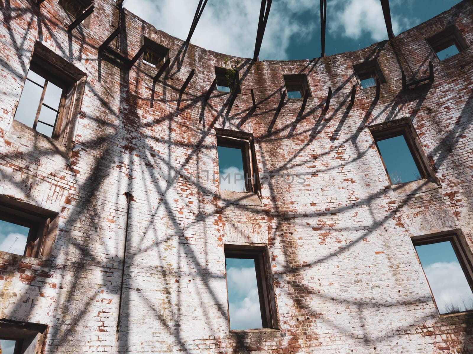 Curved brick wall of ruined building. sky is visible through the windows. part of destroyed house. old architecture