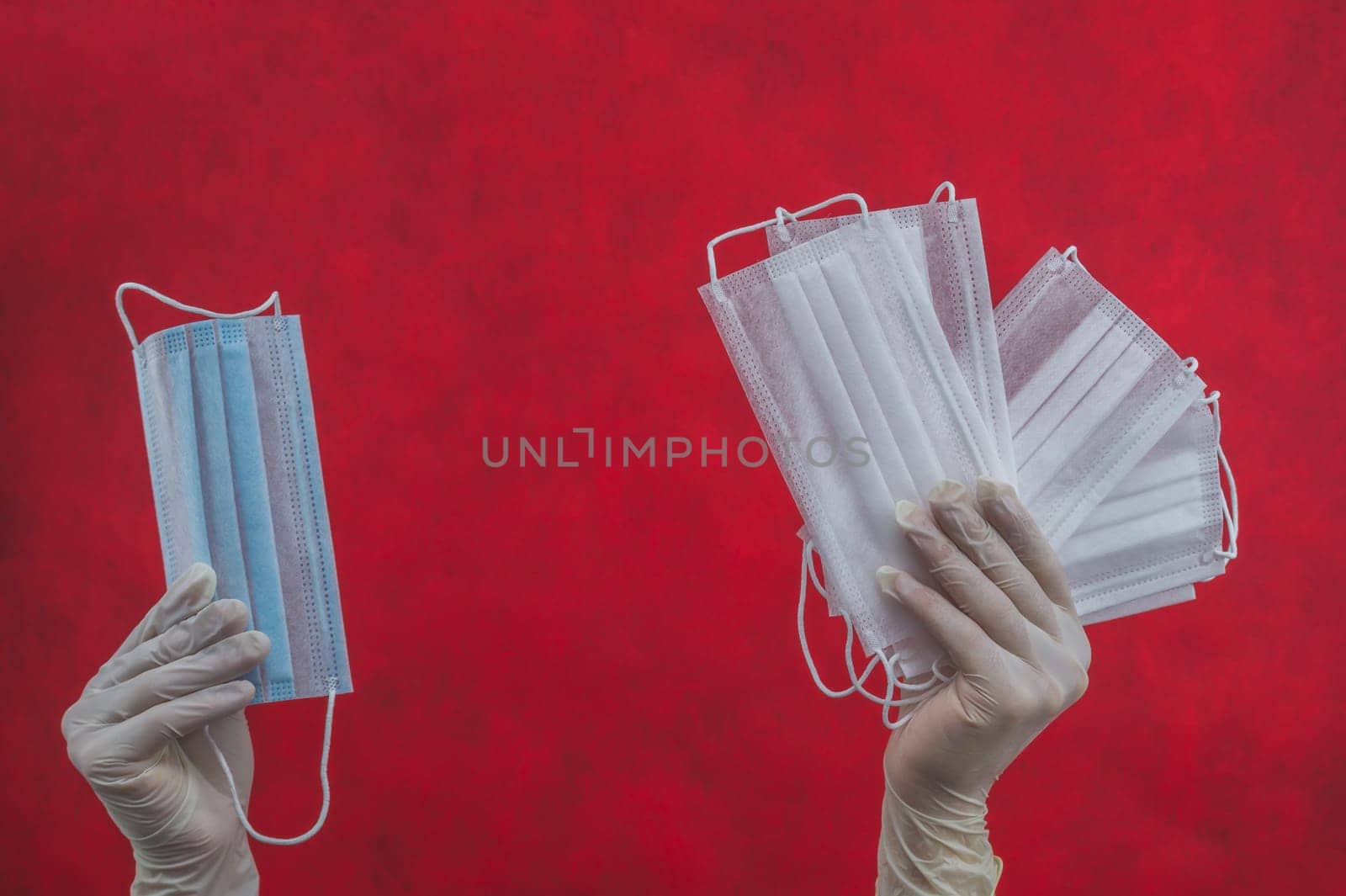 Medical masks in hands with protective. preventive measures against respiratory illness and virus. hand in white surgical glove holds disposable masks for protection gloves on a red background